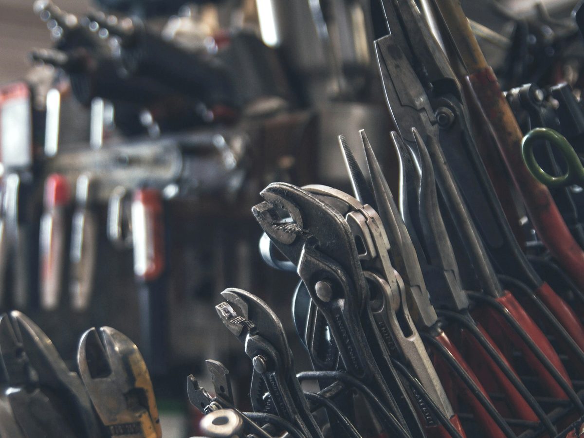 A wall of hand tools including pliers and wrenches in a workshop