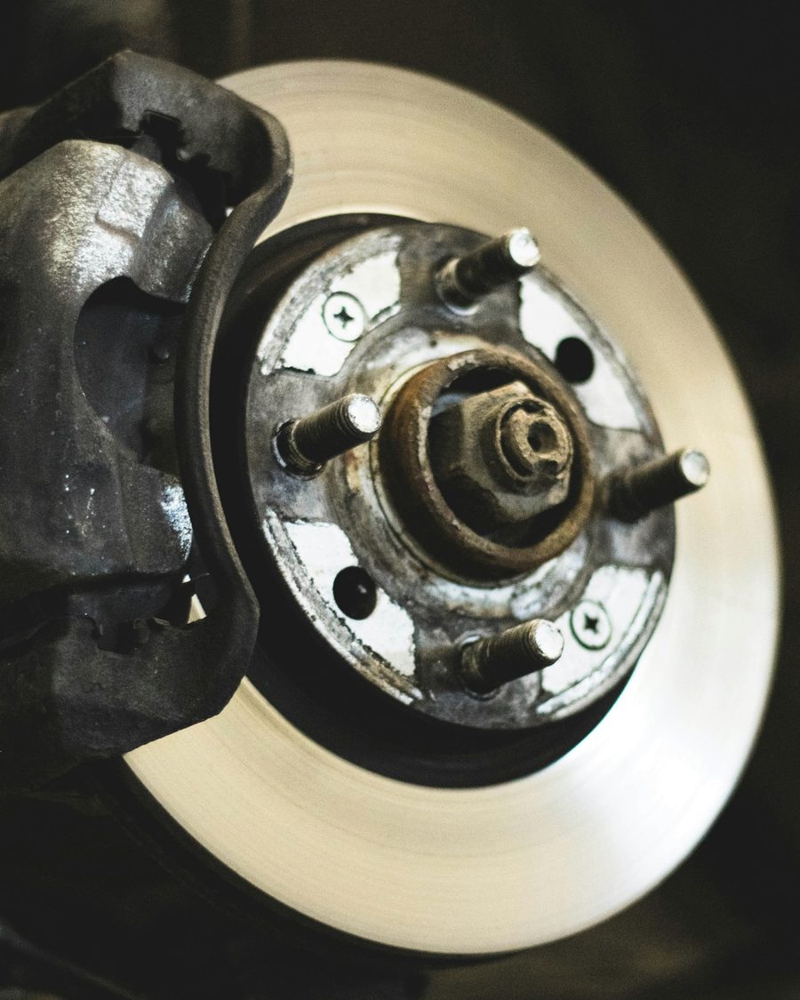 Close-up of a worn brake rotor and caliper being inspected on a hub